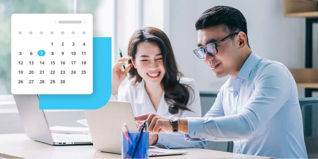 Two colleagues reviewing a laptop together beside a calendar interface, planning upcoming work.
