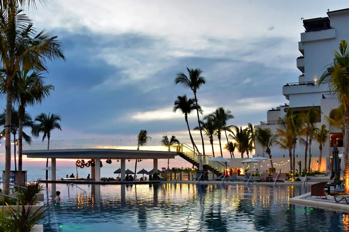 Beachfront retreat with palm trees and a pool at sunset.